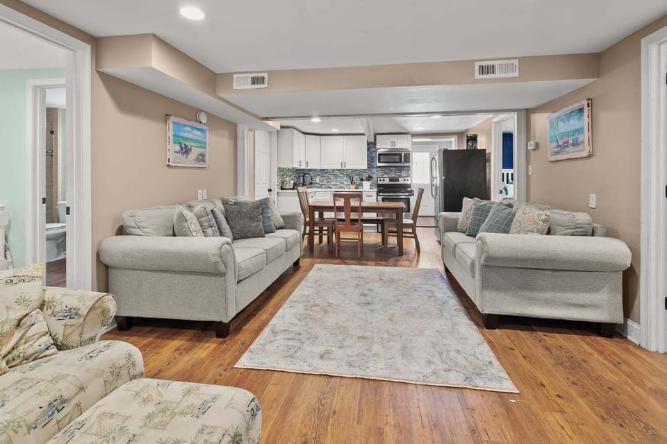 Gathering space with sofas, a dining table and the kitchen beyond at Rising Tide in Cherry Grove