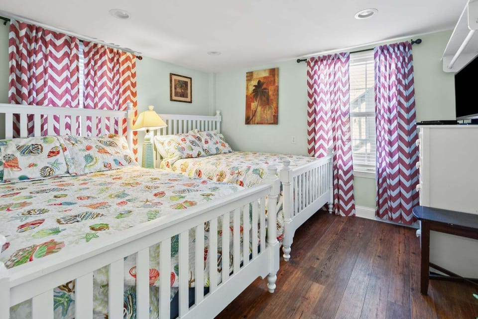 Bright chevron curtains and two beds in a green bedroom at Rising Tide, Cherry Grove