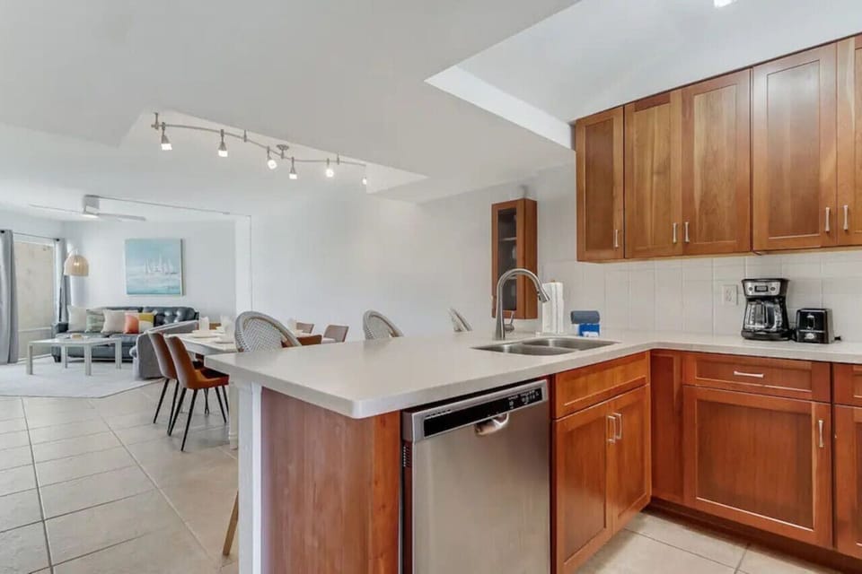 Modern kitchen with granite counters, stainless appliances, and breakfast bar opening to dining and living areas – fully equipped with cookware and essentials for Butler Beach