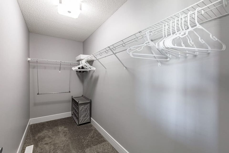 This queen bedroom offers a dresser and walk-in closet for added convenience. Guests enjoy a tidy and relaxing environment.