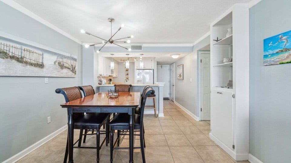 This inviting dining area features a high-top table for six, coastal décor, and modern lighting.