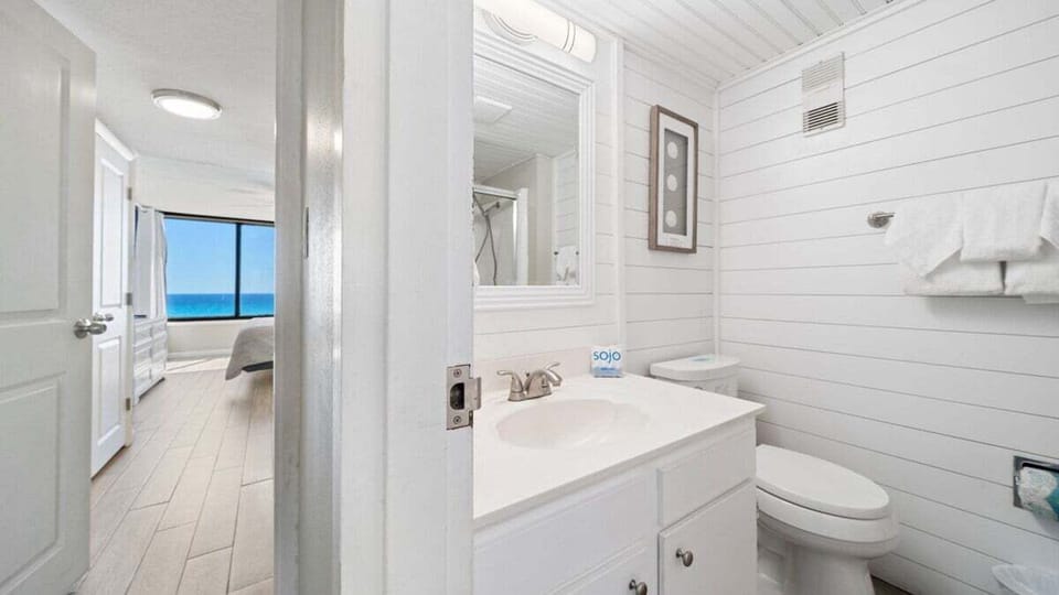 Bright coastal bathroom with crisp white finishes and direct access to the beachfront master bedroom—clean and simple, ideal for freshening up after a sunny day.