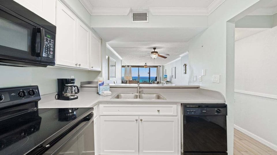 Fully equipped kitchen with modern appliances and pass-through window offering ocean views—ideal for meal prep while staying connected to the living area and beach vibes.