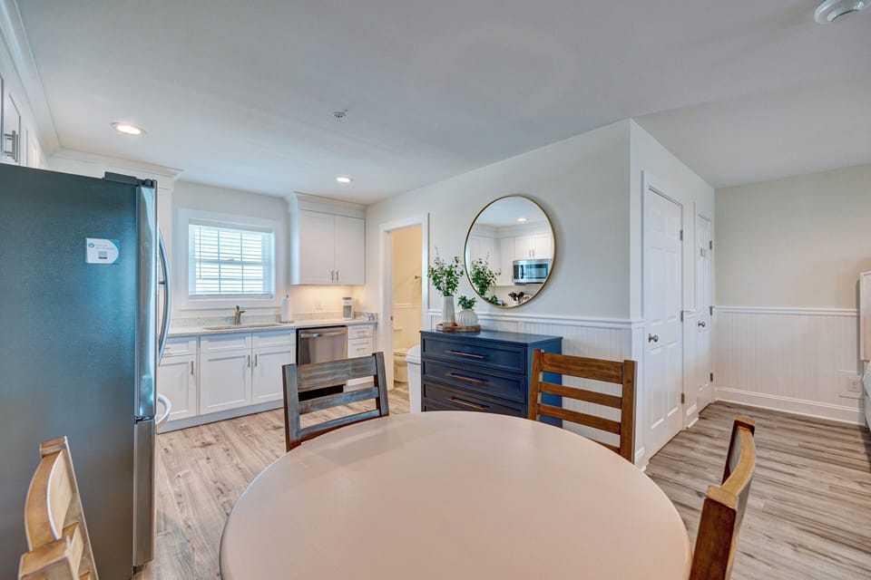 Your open-plan kitchen and dining area combines sleek white cabinets, modern appliances, and warm wood finishes for memorable meals together.