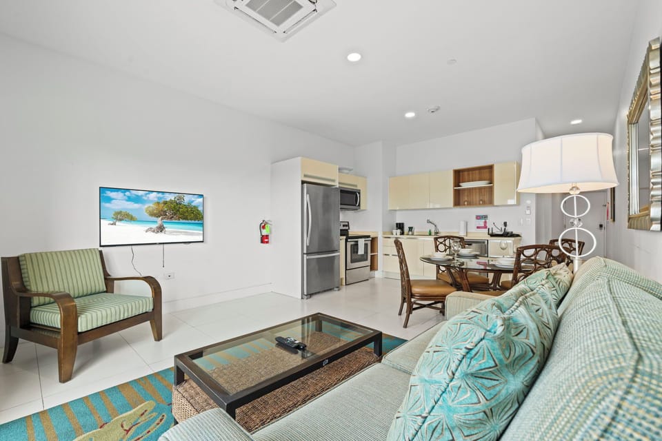 Open concept kitchen featuring sleek stainless steel appliances & counter space - Cozy dining area with a glass top table is ideal for enjoying meals or gatherings - Seamless flow between the kitchen & living space creates a  welcoming environment