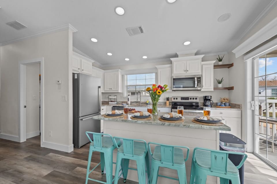 Enjoy meals together in this bright kitchen featuring a large island and sliding doors that open to the sunny porch. ☀️