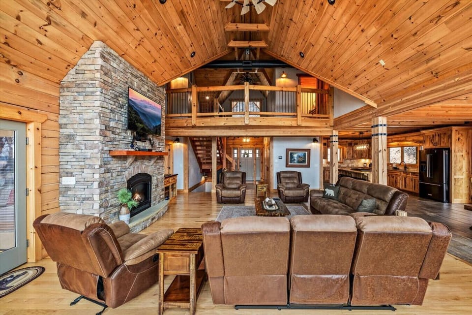 Relax in plush seating while taking in the warm wood tones, vaulted ceilings, and the glow of the fireplace in this spacious, open-concept living area.