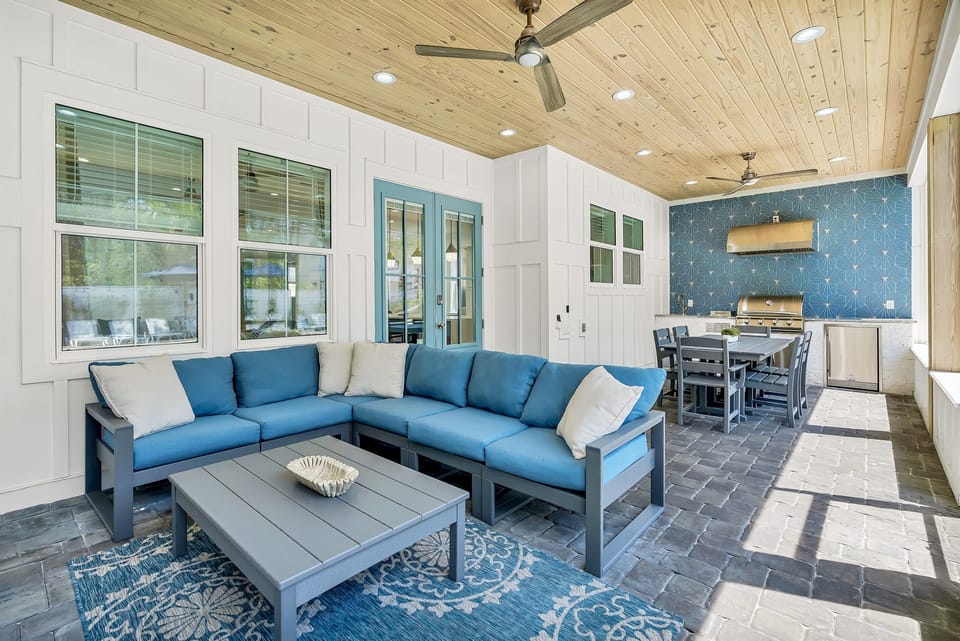 Screened in porch with built-in gas grill, sink, fridge, dining table, lounge seating, and a 4K Smart TV
