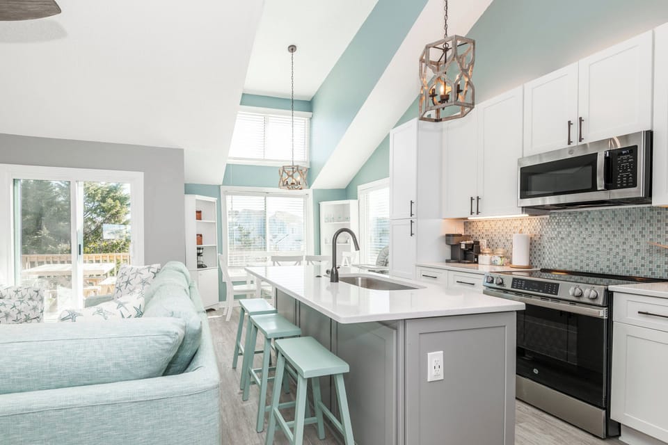 Modern open-concept kitchen with stainless steel appliances, and a spacious island with bar stools.