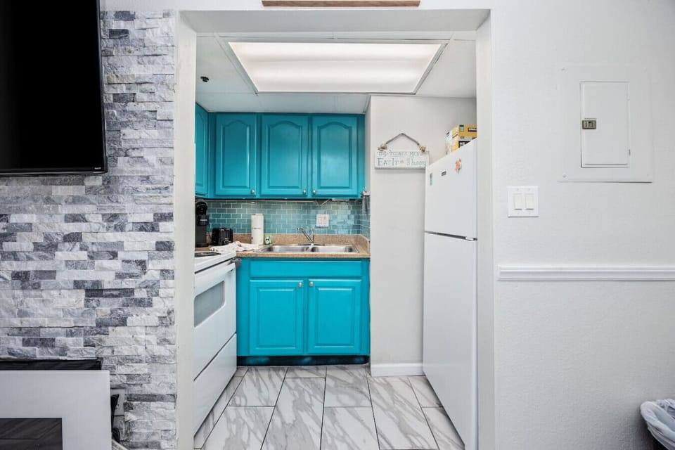 A bright beach-themed kitchen featuring a stove, oven, refrigerator, microwave, and all cooking essentials. Fully stocked with dinnerware and silverware, this stylish space is perfect for preparing meals and enjoying a cozy coastal dining experience.