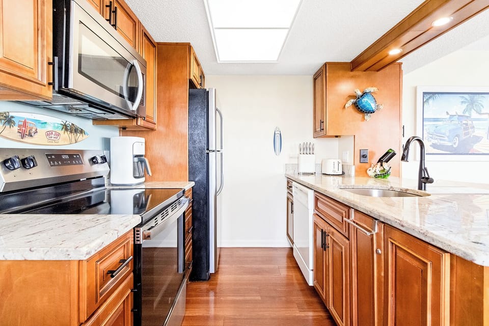 Fully-equipped kitchen with ample cabinetry, refrigerator, microwave oven, stove, coffee maker and blender.