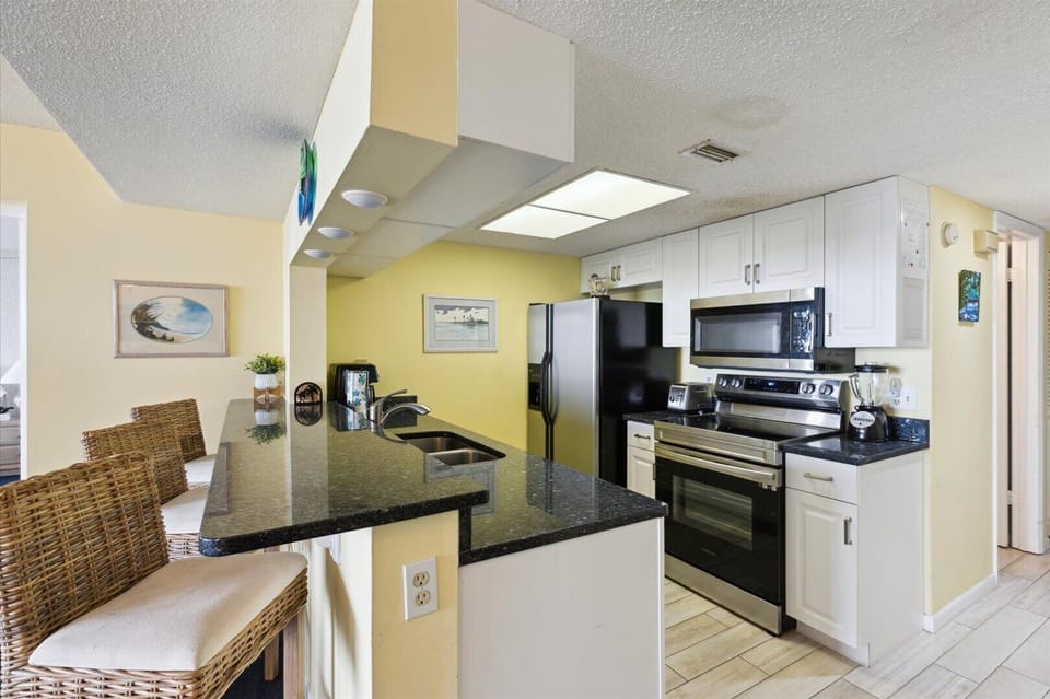 Kitchen area with ample cabinetry, counter island with bar stool chair and equipped with appliances.