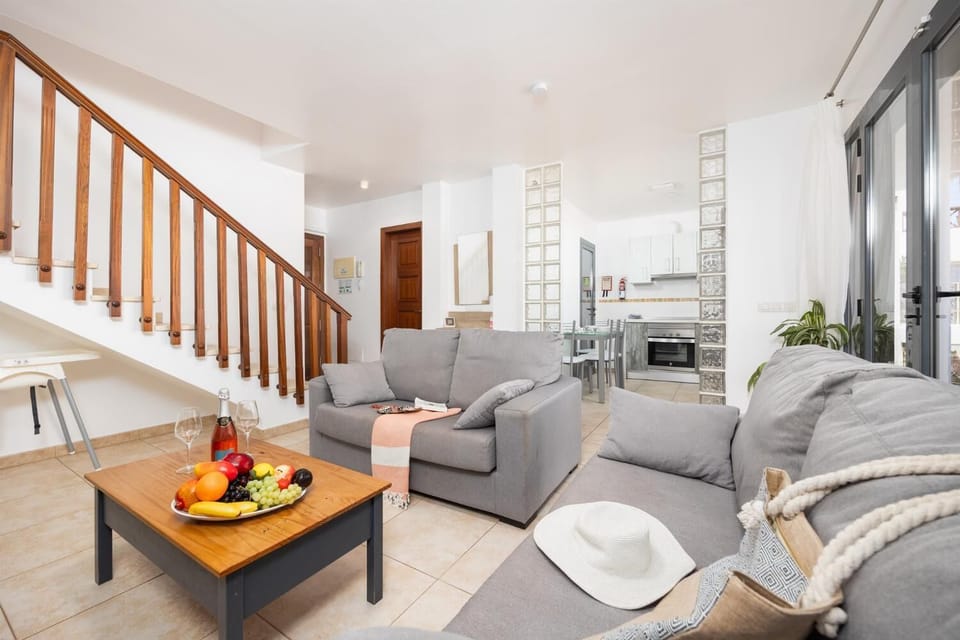 Open-plan living room with sofas, dining area, kitchen, A/C, WiFi internet, and satellite TV