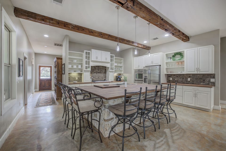 A spacious, open kitchen featuring rustic stone accents, a large island, and modern amenities for cooking and gathering.