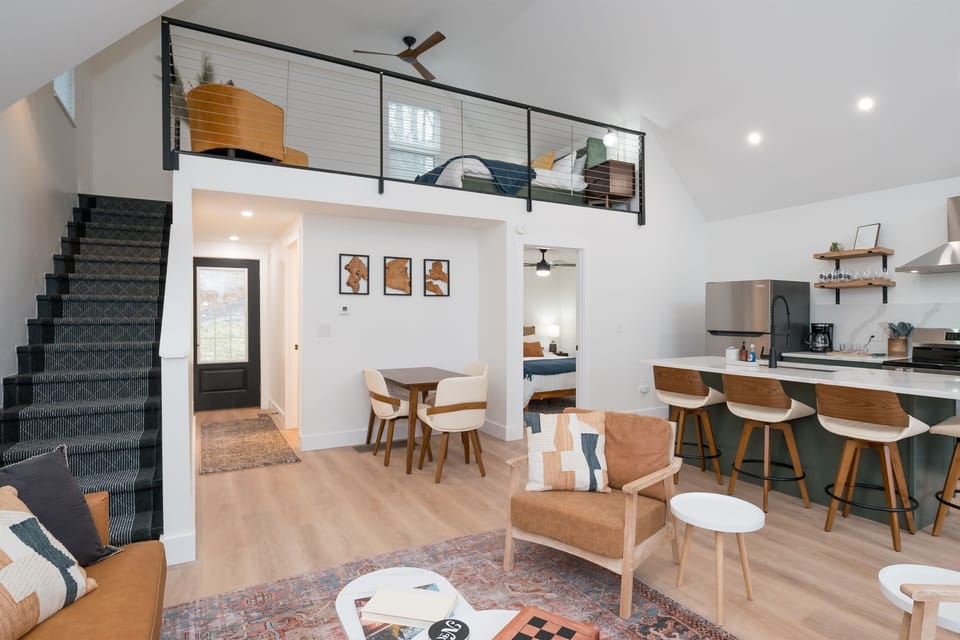 Main floor from above at Hemingway — open concept layout, loft railing visible, staircase to lower level