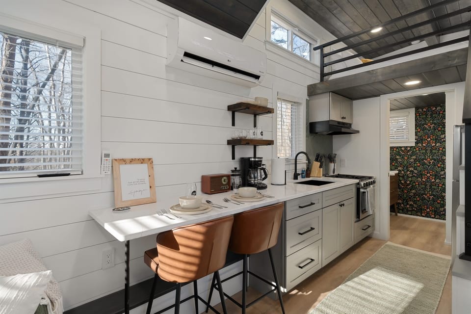 Main floor overview at Hughes — kitchenette, living area, and lofted queen bed above all in one open layout