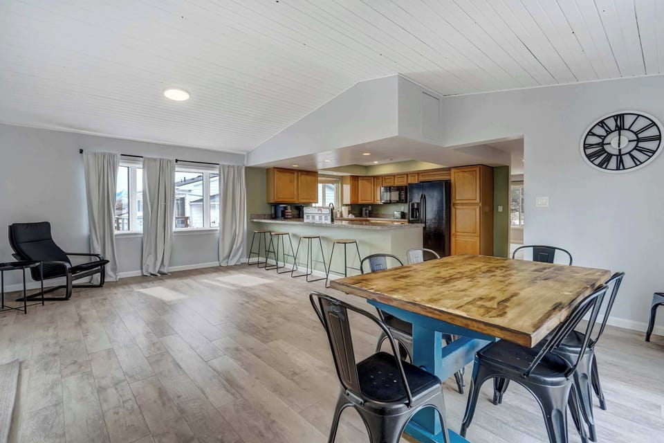 Spacious open-concept dining and kitchen area with a large wooden table, bar seating, and plenty of natural light—perfect for gathering and enjoying home-cooked meals.





