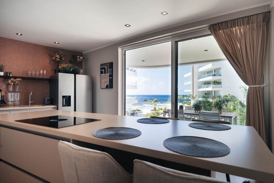 Modern open kitchen with a spacious island, perfect for casual meals, with sliding doors opening to the balcony and ocean views.