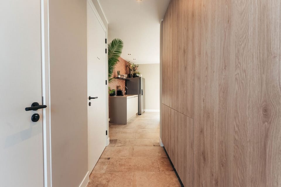Step into a warm, welcoming hallway that leads straight to a modern kitchen with natural textures and cozy touches—perfect for settling in.