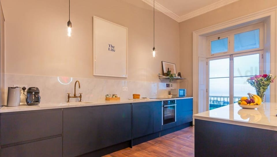 A stunning, light-filled kitchen featuring a sleek marble splashback and premium integrated appliances, perfectly blending period character with modern luxury.