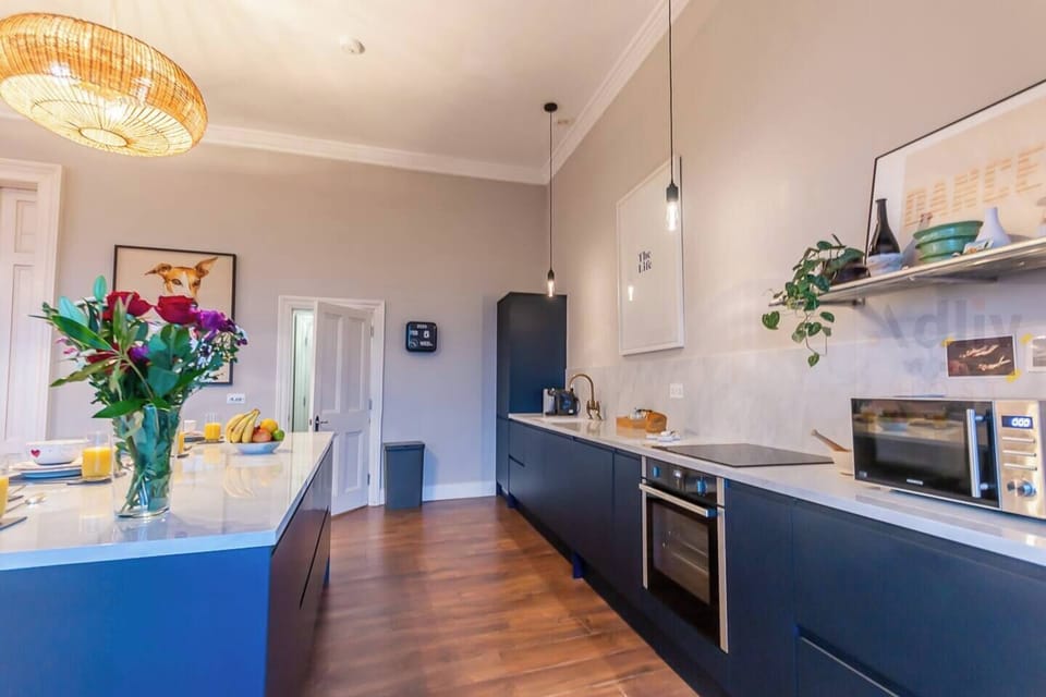 A state-of-the-art designer kitchen featuring sleek navy cabinetry, marble-effect finishes, and high-end appliances for a seamless culinary experience.