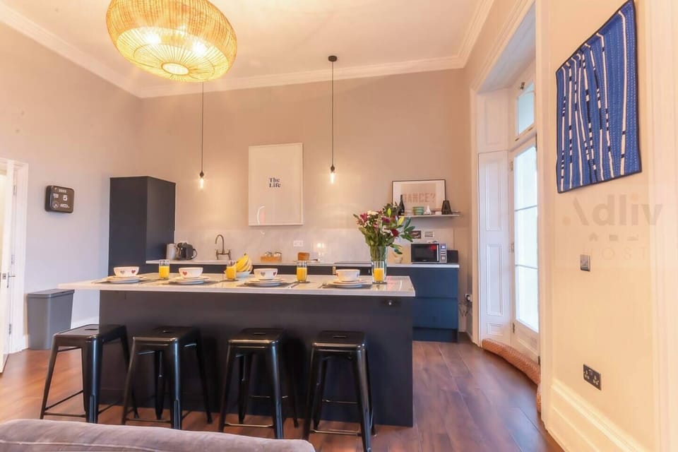 A sleek, contemporary kitchen island designed for social mornings and stylish entertaining in a bright, high-ceilinged period setting.