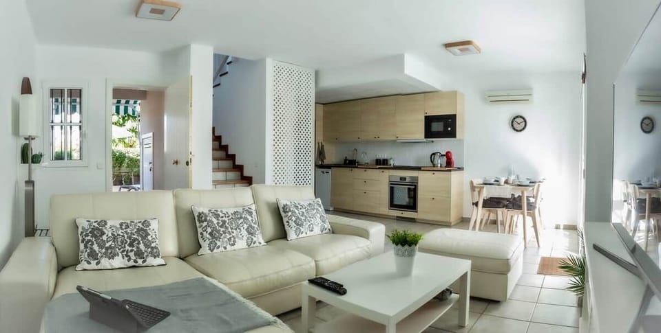 Diáfano y luminoso salón con un confortable sofá, mobiliario práctico, mantas, iluminación led ajustable, climatización y smart TV de 50" 