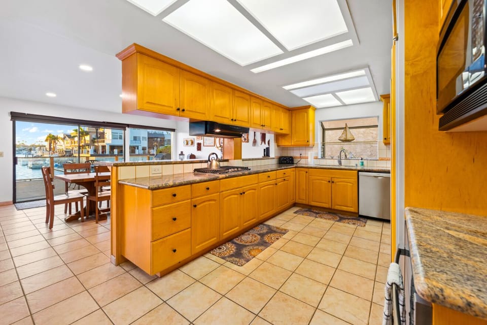 Spacious kitchen with warm wood cabinetry, granite countertops, and stunning water views