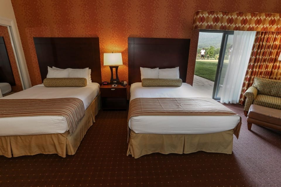 Spacious room with two plush beds and a private balcony, perfect for families or groups.
