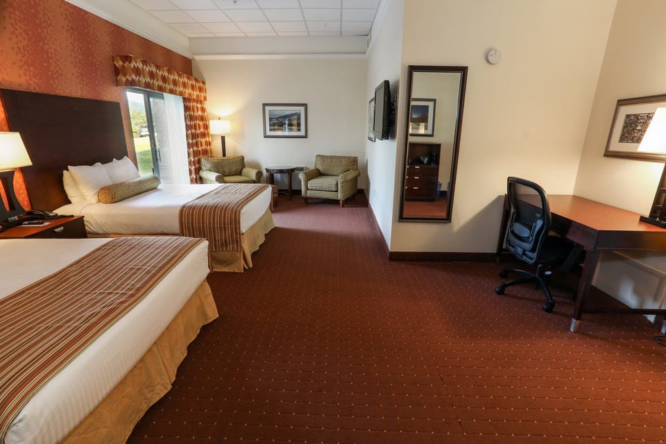 Comfortable room featuring two cozy beds, a work desk, and natural light from large windows.