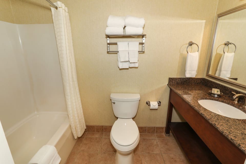 Modern bathroom featuring a shower/tub combo, granite vanity, and fresh towels for a relaxing stay.