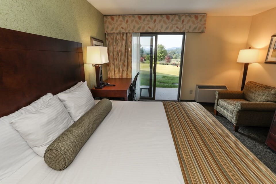 Cozy guest room with warm décor, plush bedding, and a private patio overlooking scenic views.