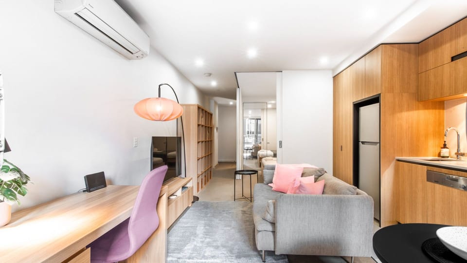 Seamless urban living featuring warm timber cabinetry, air conditioning, and a beautifully arranged lounge area.
