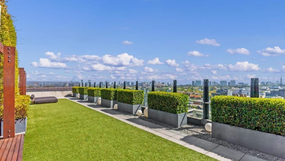 Soak in the sun on a manicured rooftop lawn boasting panoramic skyline views and modern glass balustrades.