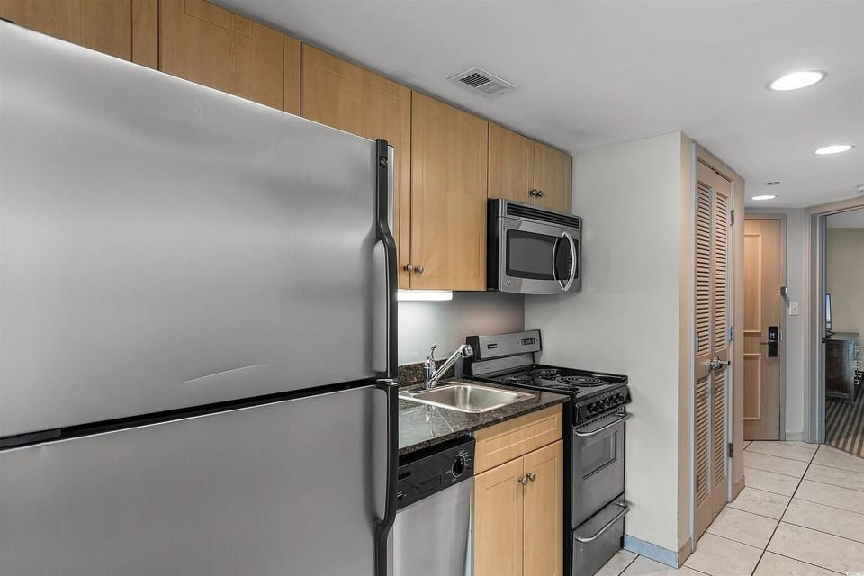 This sleek kitchenette features modern light wood cabinetry