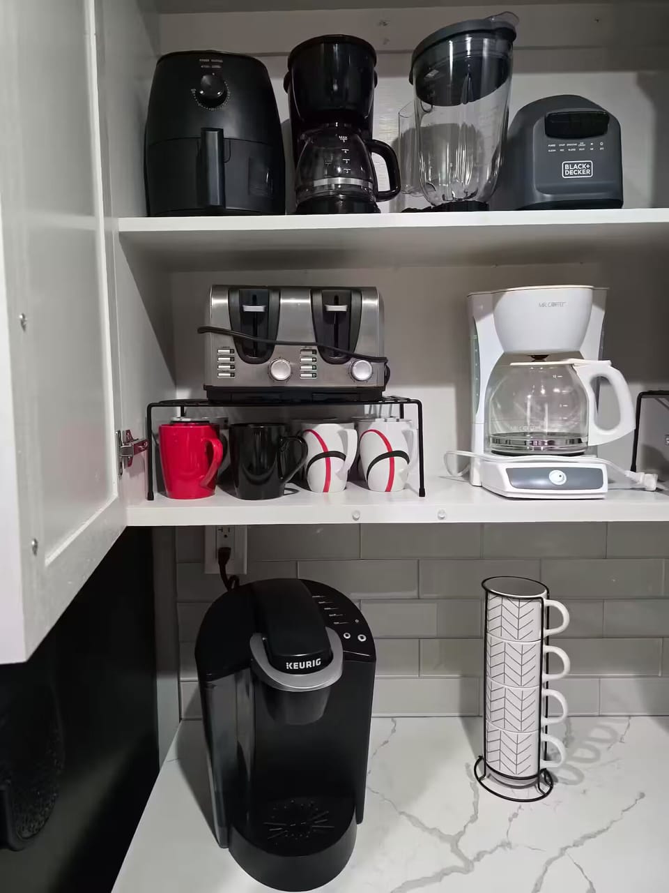 Several coffee maker options, full toaster, small air fryer and a blender. 