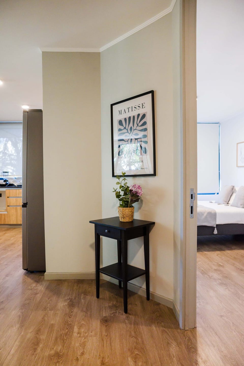 Charming entryway with artistic flair and natural light, leading to a cozy bedroom and modern kitchen.