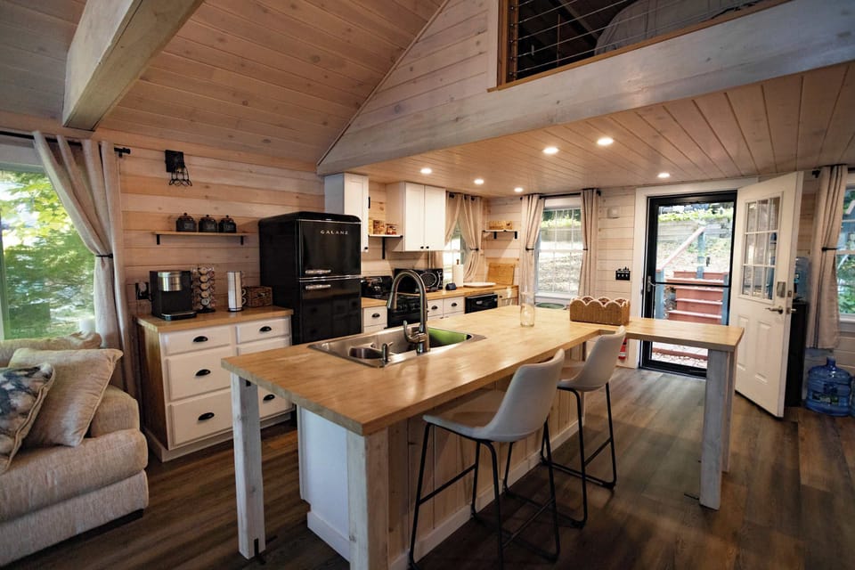 Open-concept kitchen with large island seating, modern appliances, and warm cabin finishes.