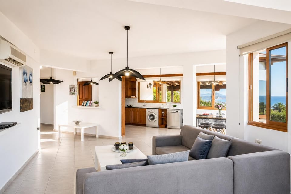 Open-plan living room with sofa, dining area, kitchen, A/C, WiFi internet, and satellite TV