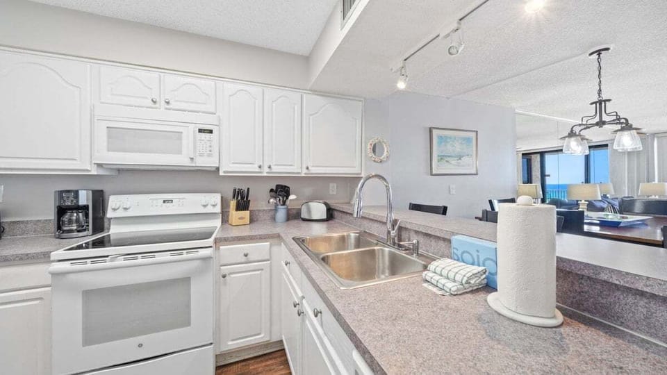 Cook with ease in this fully equipped kitchen with white cabinetry, modern appliances, and all essentials for your beach stay.