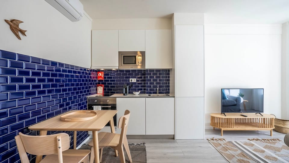 Stylish kitchenette with a bold blue backsplash, modern appliances, and a cozy dining area. The open-plan design creates a bright and inviting space for a comfortable stay.
#ModernKitchen #CozyLiving #PortoStay #DesignDetails #TravelPortugal