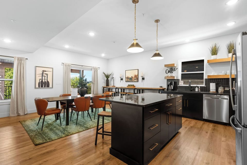 - Channel your inner chef in a stunning kitchen with sleek black cabinets
- Large island with barstools invites casual meals, cocktails, or friendly conversations
- Stainless steel appliances and open shelving make cooking effortless and enjoyable