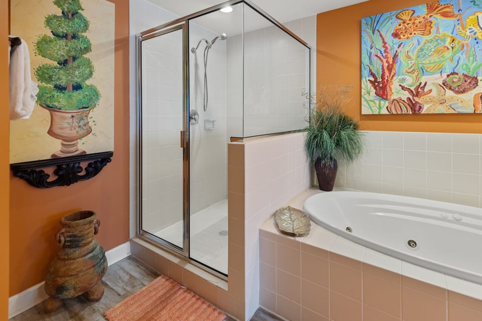 Indulge in your spa-like bathroom featuring a luxurious jetted tub and separate glass shower, surrounded by vibrant artwork and decorative touches.