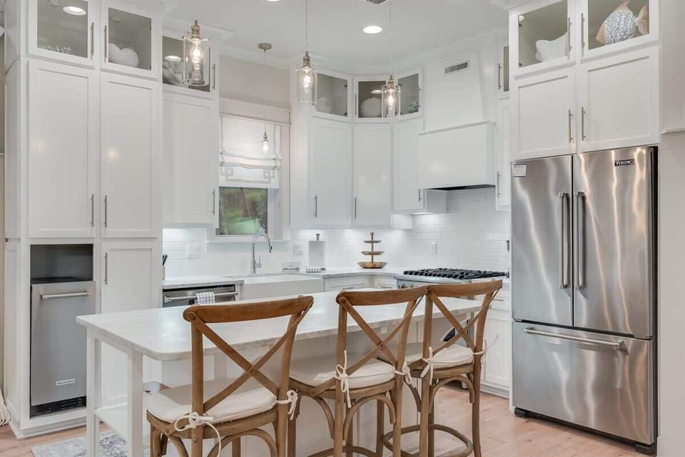 - Modern kitchen with sleek white cabinetry and stainless steel appliances - Fully equipped with a gas stove, large fridge, and extra storage space for all your needs - Perfect for preparing meals or enjoying a casual breakfast at the stylish island