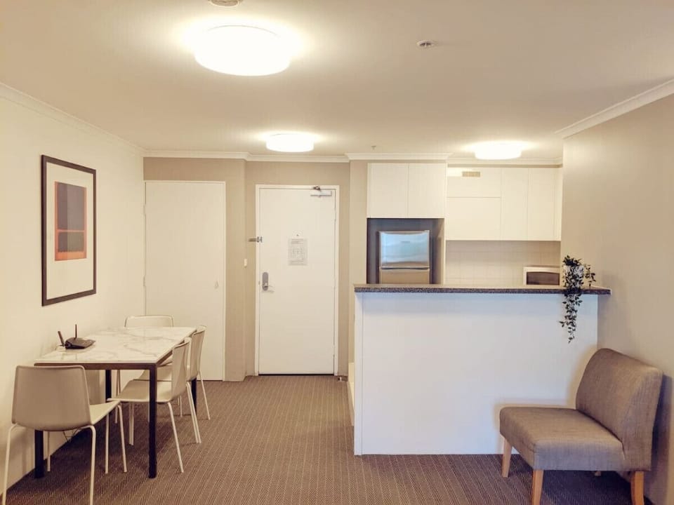 The dining area boasts a sleek table that seats four, adjacent to a modern kitchen outfitted with contemporary appliances and stylish decor.