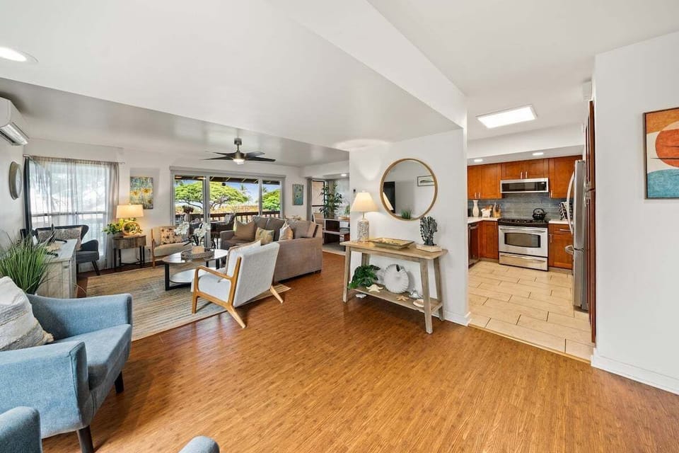 Open-concept living and dining area with hardwood floors, ceiling fans, and panoramic garden views.