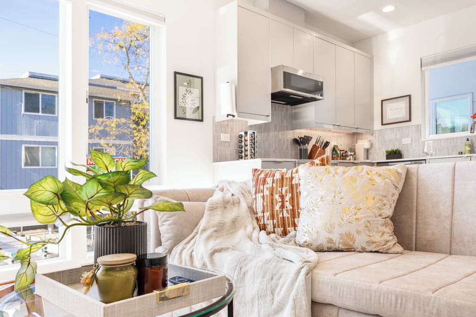 The living room features comfortable seating and is brightened by a lush plant, adding a touch of natural warmth and tranquility to the space.