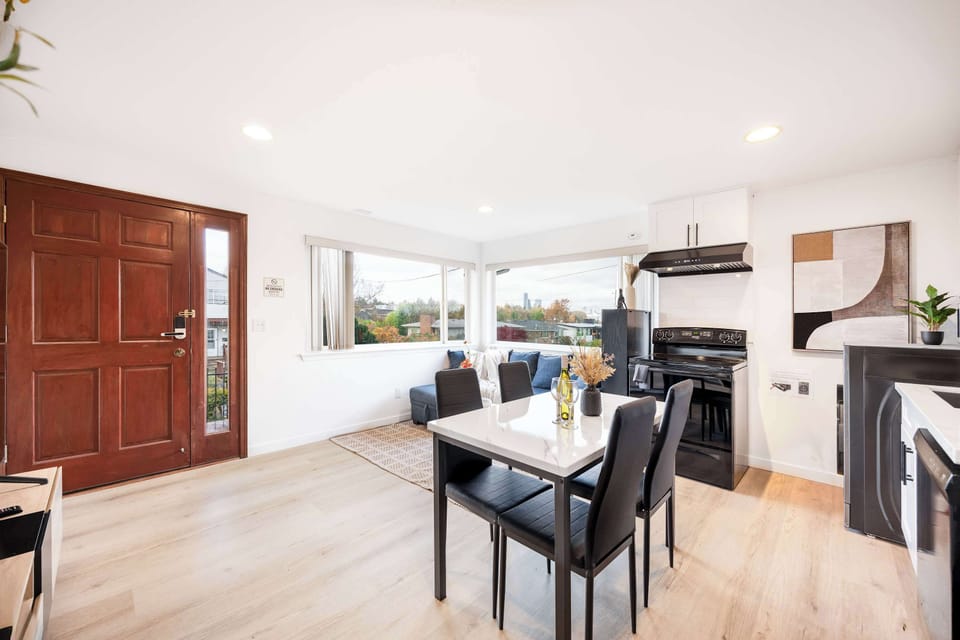 An open-concept space where the dining table for four sits perfectly between the cozy living room and the functional kitchen, creating a seamless flow for dining, relaxing, and entertaining.