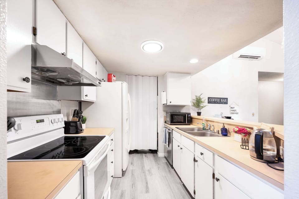 This bright and practical kitchen is fully stocked with all the essentials, including a stovetop, microwave, and spacious countertops. The open design ensures easy interaction with the dining and living spaces.
