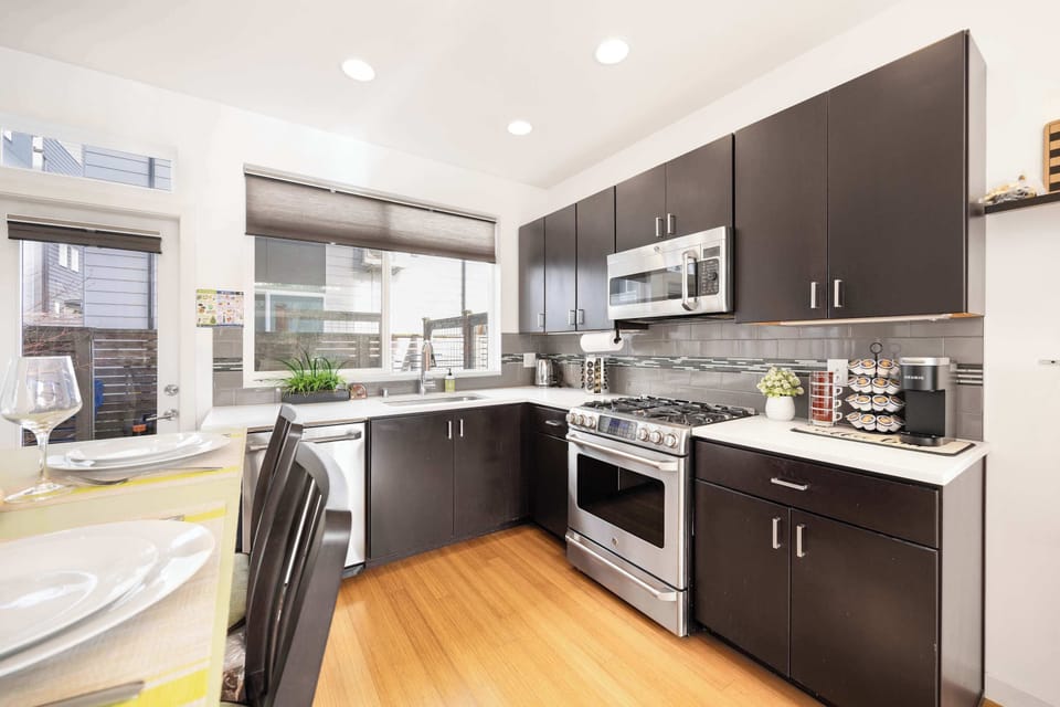 Cook in style with stainless steel appliances, sleek dark cabinetry, and a cozy dining setup.